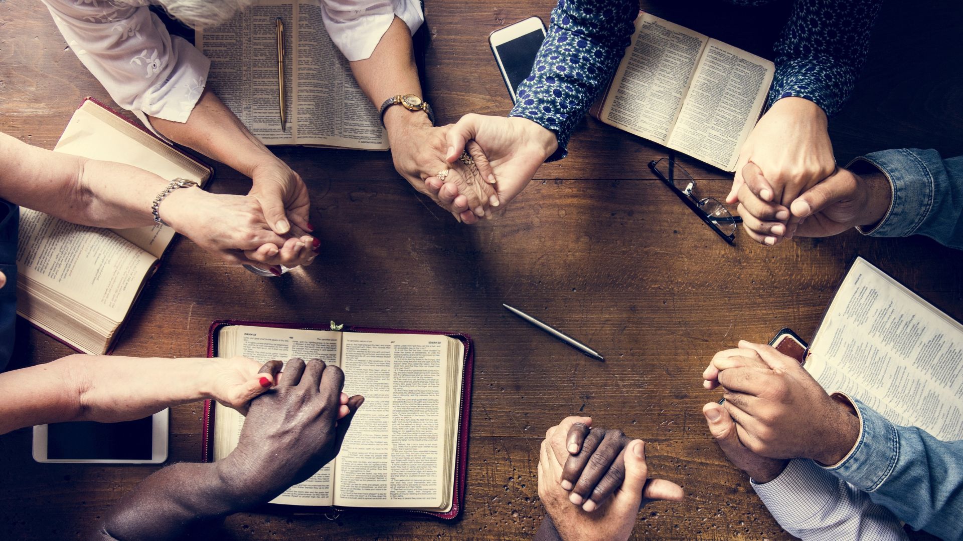 people joining hands and bibles on the table